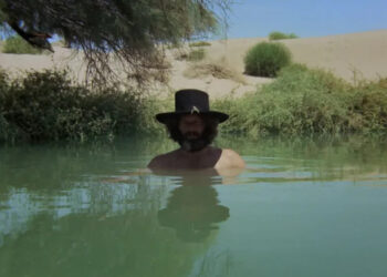 Alejandro Jodorowsky as El Topo stands with his head emerging from a pool of water in El Topo