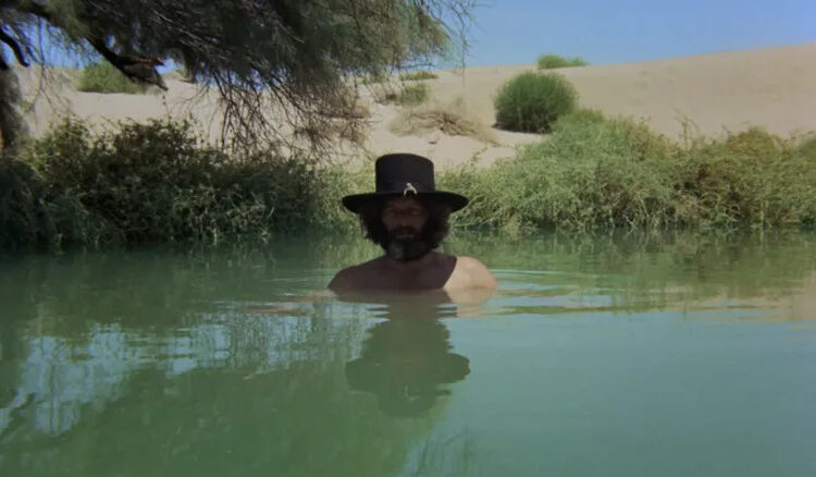 Alejandro Jodorowsky as El Topo stands with his head emerging from a pool of water in El Topo