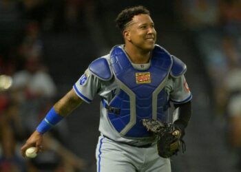 Salvador Perez, holding the ball and wearing a glove on his other hand, smiles after catching a pop foul.