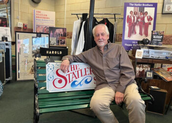 Don Reid, a founding member of the Statler Brothers, sits on a bench inside a display of memorabilia from the country music group.