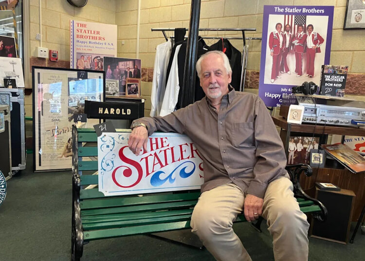 Don Reid, a founding member of the Statler Brothers, sits on a bench inside a display of memorabilia from the country music group.