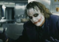 Heath Ledger's Joker holds out his hands in a kitchen in The Dark Knight Rises