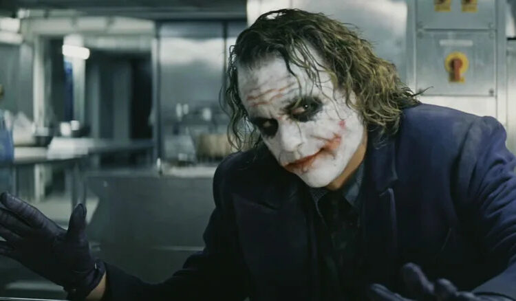 Heath Ledger's Joker holds out his hands in a kitchen in The Dark Knight Rises