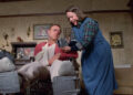 Paul sitting in a wheelchair next to Annie in Misery