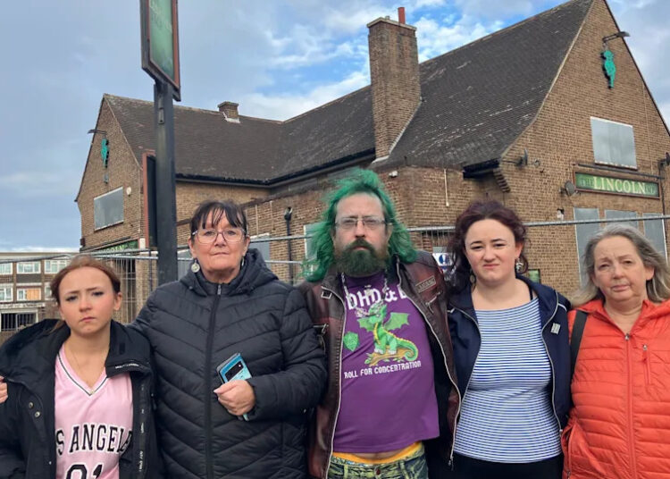 Five people standing in front of a derelict pub, the Lincoln Imp. There are three women, one man and a girl.