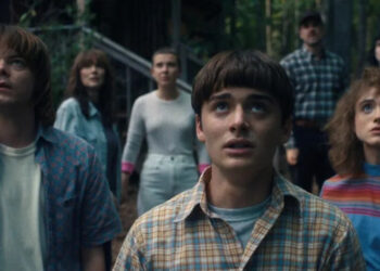 Jonathan, Joyce, Eleven, Will, Hopper, Mike, and Nancy look up at the sky in Stranger Things by the duffer brothers