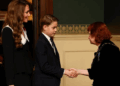 Prince George shakes hands with a woman at the start of the Festival of Remembrance