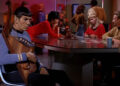 Spock holding a musical instrument as his crewmates play card in "Star Trek"