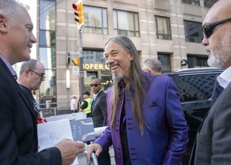 The Tragically Hip's Rob Baker signs a fan's poster after a public sing-along with Choir! Choir! Choir! at the Toronto International Film Festival, in Toronto, on Thursday Sept. 5, 2024. THE CANADIAN PRESS/Paige Taylor White