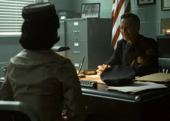 Taylour Paige as Charlotte Hanlon seated across Peter Outerbridge as Police Chief Clint Bowers in his office in It: Welcome to Derry