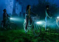 Arian S. Cartaya as Rich, Clara Stack as Lilly Bainbridge, and Amanda Christine as Ronnie Grogan riding bikes in a cemetery at night in It: Welcome to Derry