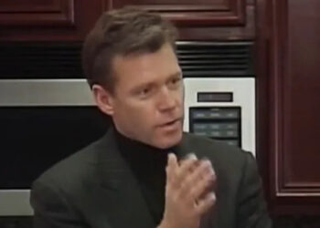 Chris Hanson holds his hand up as he talks in a kitchen in To Catch A Predator