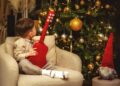 A little boy sitting in a chair next to a christmas tree
