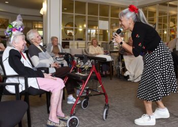 Inside an aged care residential property, a woman sings to the elderly.