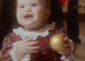 Princess Ines wearing a plaid dress holding an ornament