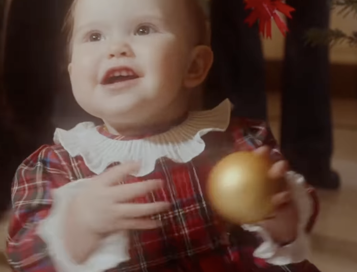 Princess Ines wearing a plaid dress holding an ornament