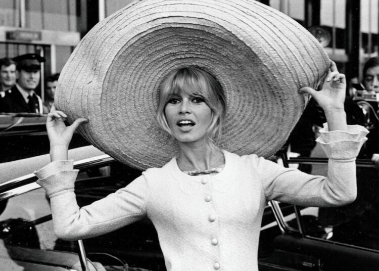 French actress Brigitte Bardot poses with a huge sombrero she brought back from Mexico, as she arrives at Orly Airport in Paris, France, on May 27, 1965. (AP Photo/File)