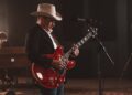 man playing a red guitar