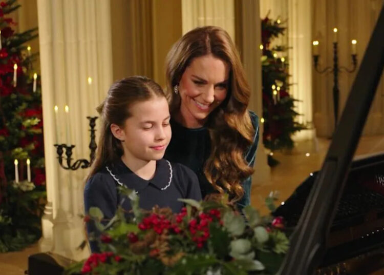 Princess Charlotte and Catherine, The Princess of Wales, sit smiling at a piano as they perform at for a Christmas Carol service