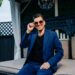 Man in blue suit and sun glasses sitting on a couch outside