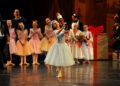A young ballerina portraying Clara lifts the Nutcracker doll during a Santa Cruz ballet performance.