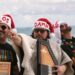 Photo of men wearing christmas hats at the beach.