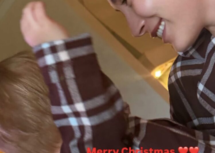 a child wearing a checkered shirt raises a hand festive message included