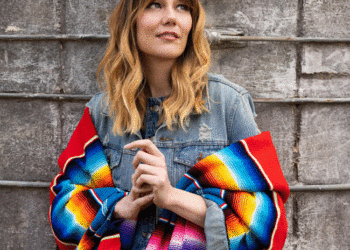 Molly Tuttle, wearing a denim jacket and brighly colored shawl, will perform at the Arlington Theatre, Sunday, Dec. 7 in support of her new album "So Long Little Miss Sunshine." (Ebru Yildiz photo)