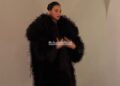 model wearing a dramatic black coat and a red dress