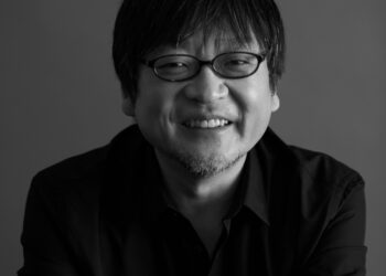 A black-and-white photo of film director Mamoru Hosoda.