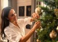 Meghan Markle decorating a Christmas tree in her Netflix holiday special, carefully placing ornaments while smiling and enjoying the festive activity.