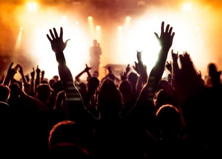 silhouettes of concert crowd in front of bright stage lights