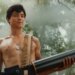 Miles Heizer as Cameron Cope, shirtless with an ammunition belt over his shoulder and a large weapon, in a misty forest.