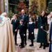 The royal family standing in front of a priest in a church