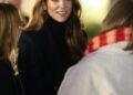 Kate Middleton wearing a plaid coat talking to a woman