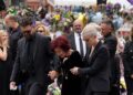 Jack, Sharon and Kelly Osbourne embrace as they view the messages and floral tributes left at the Black Sabbath Bridge bench in Birmingham (Joe Giddens/PA)
