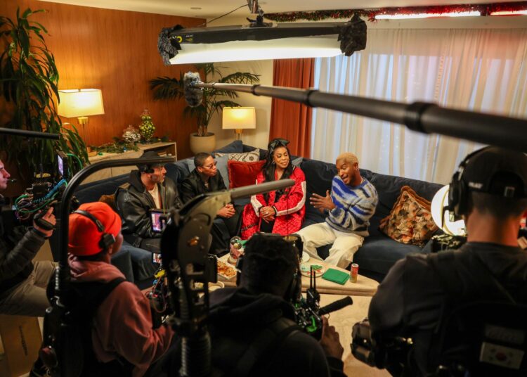 Scott Evans at home with guests sitting around him on couch