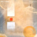Staran Gold From Ruins. The cover presents an abstract landscape with muted beige, gray, and gold tones. Two white rectangular shapes and a small red square sit near the center, while circular forms hover around the edges. A lone, dark human figure stands atop a pale ridge in the upper right. The titles Gold From Ruins and Staran appear in white text.