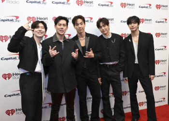 photo of a group of Korean singers in front of a step and repeat.