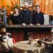 Three people stand behind a bar with two animatronics at a table before them.