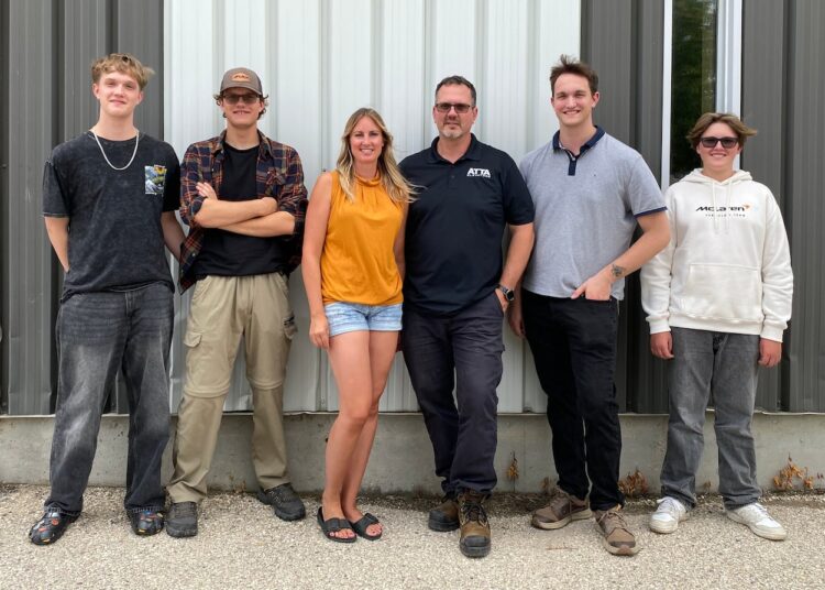 Six people stand outside a small-town theatre in Manitoba.