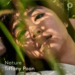 A person lies among green plants, with shadows of leaves across their face. The text Nature Tiffany Poon appears at the bottom left.