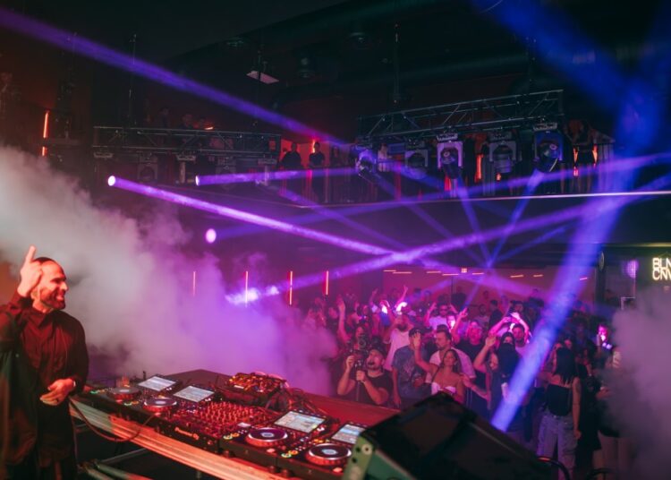 Photo of a DJ on stage in front of a dancing crowd.