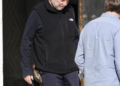 Timothy Busfield in a black vest and dark pants, accompanied by a man in a light blue shirt.