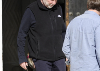 Timothy Busfield in a black vest and dark pants, accompanied by a man in a light blue shirt.