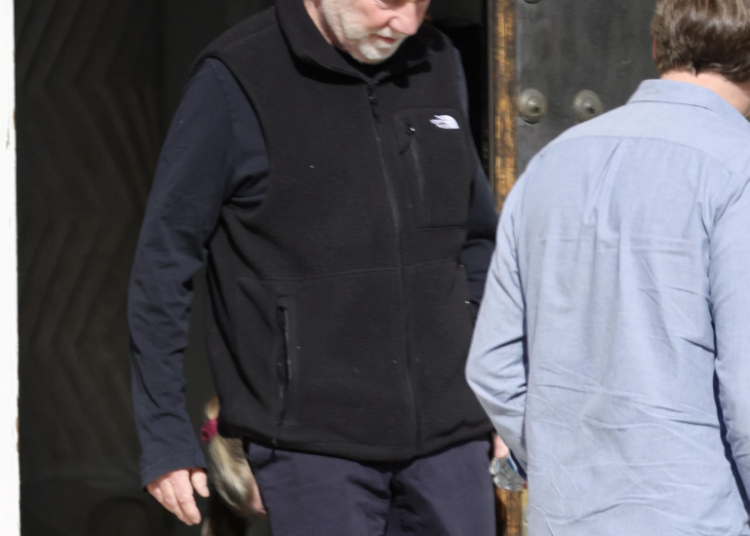 Timothy Busfield in a black vest and dark pants, accompanied by a man in a light blue shirt.