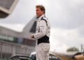 A man in a white racing jumpsuit surveys the track.