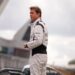A man in a white racing jumpsuit surveys the track.