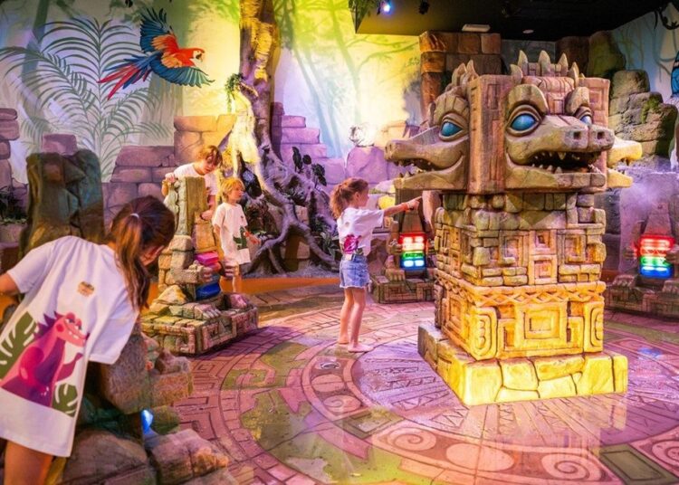 Children exploring interactive jungle-themed play area with colorful stone structures.