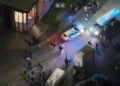 Avon and Somerset Police A drone shot of a city street at night time. A police car and a police van are visible and a number of people are milling about. Two white vans are also visible, and light is spilling from the windows of one building.